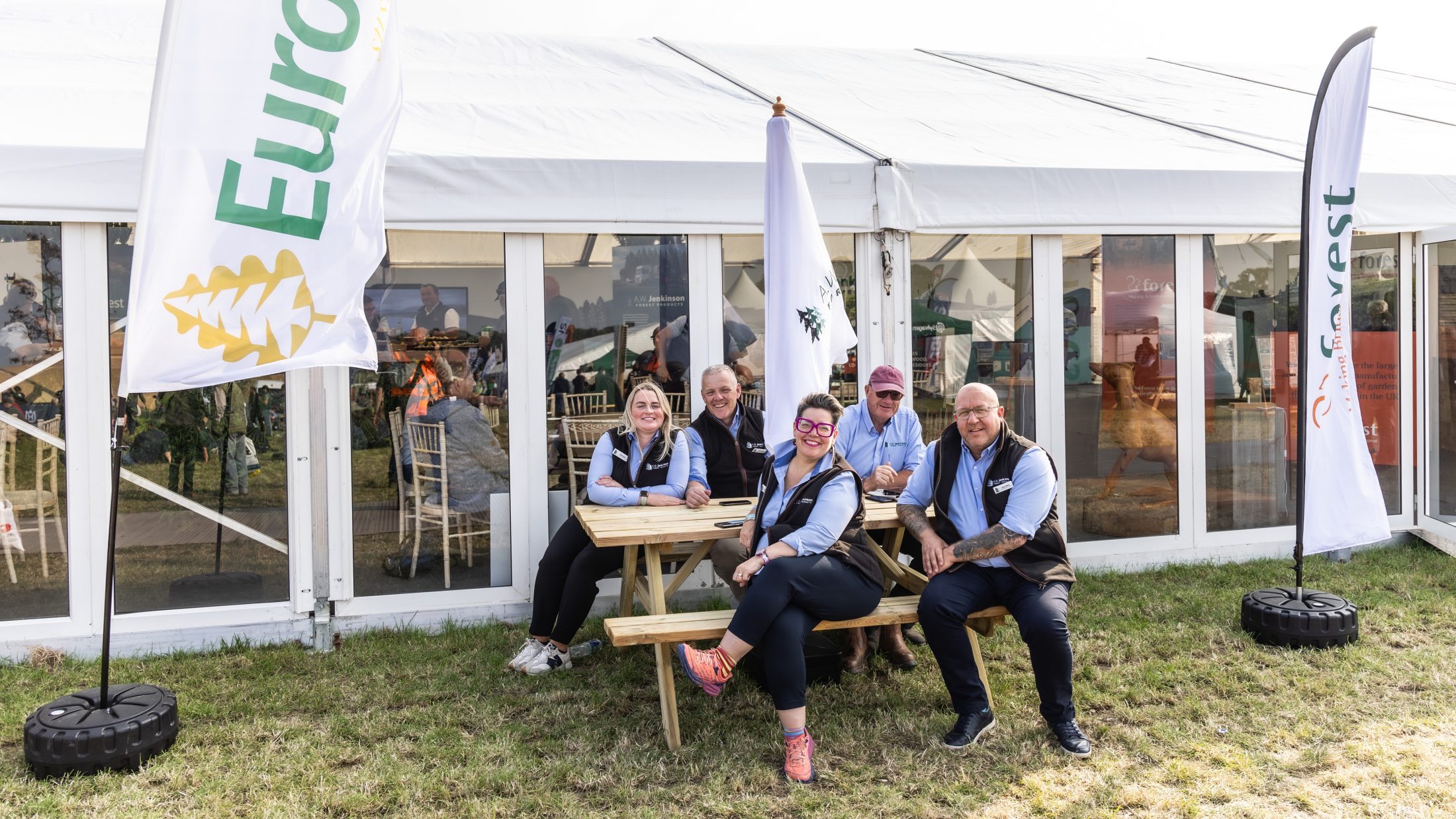 A group pic of Jenkinson workers sat on a picnic table outside the Forestry Exhibition Space