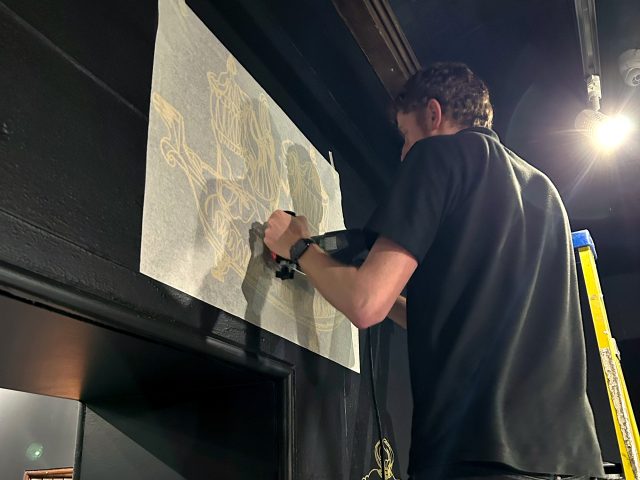 Marco from Reeds fitting the Treasure of Lowther gold vinyl wall graphics