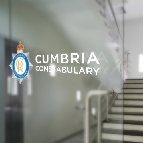 Cumbria Constabulary's new and updated police crest, featuring King Charles lll's cypher on a glass door as a window vinyl in an official building.