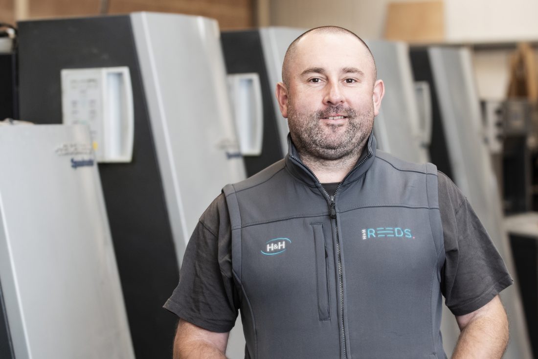 Gareth standing in front of the Litho printer in Penrith