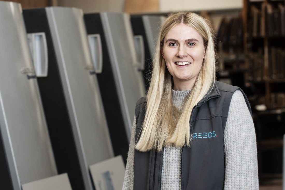 Katie standing in front of the Litho printer in Penrith