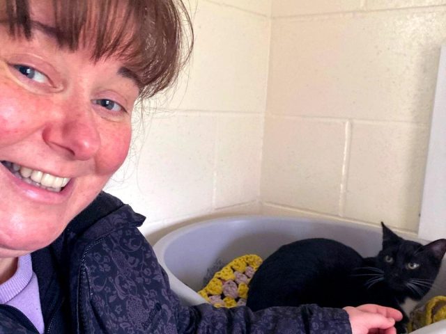 Dawn Woods posing with black cat at Eden Animal Rescue Centre.