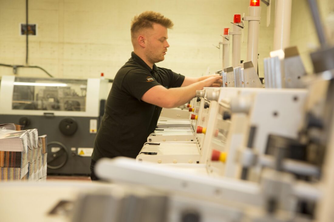 Jamie working on the machinery in the brochure stitching