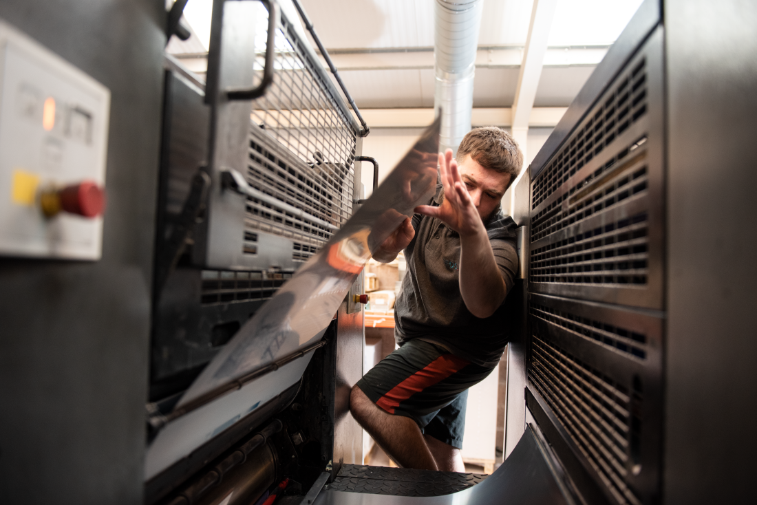 James inserting printing plates into the Heidelberg press at Reeds Printers