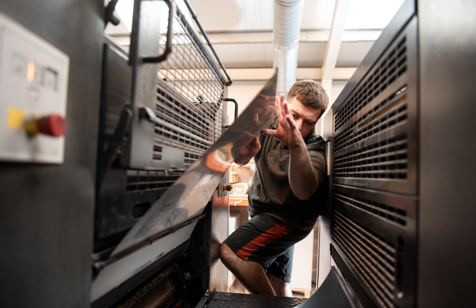 James inserting printing plates into the Heidelberg press at Reeds Printers