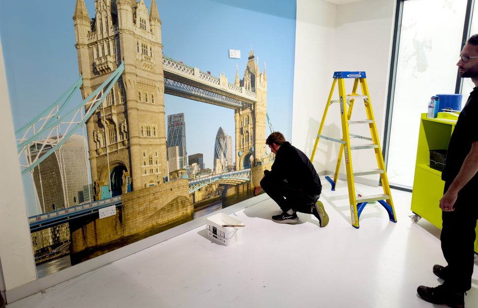 Marco installing a Digimura digital wallcovering of a photo of London Bridge at the Papergraphics headquarters.